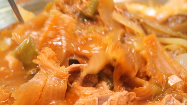 보글보글 끓은 묵은지 갈비전골의 김치와 돼지갈비를 국자로 접시에 담는 모습