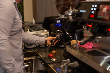 Fototapeta na wymiar Barista grinds coffee beans in electric mill, making espresso coffee
