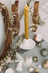 Stylish easter eggs, bunnies, cherry blossom and candle composition on rustic table. Happy Easter! Modern natural dyed marble eggs and spring flowers. Rural still life