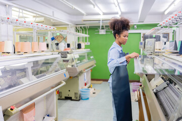 in the American textile industry Inside, a female designer holds a laptop and checks the sewing machine system. Around are spools of thread, a material used to produce clothing for export.