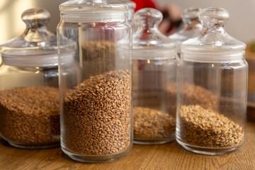Various types of malting malt in glass pots on a wooden tray.