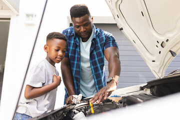 African American father teaches a son about car maintenance