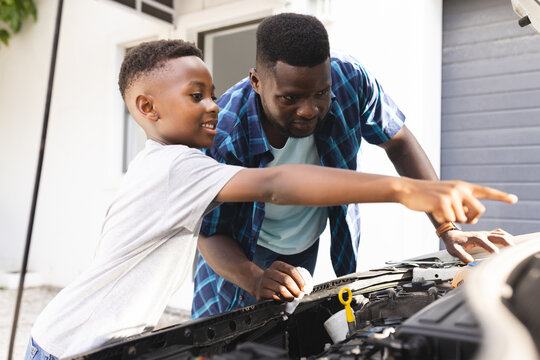 African American father and son work on a car engine together