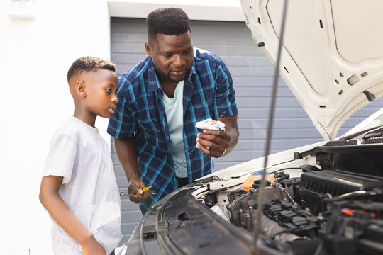 African American father teaches a son about car maintenance