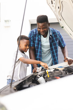African American father and son work on a car engine together