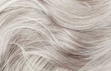 Blond hair close-up as a background. Women's long blonde hair. Beautifully styled wavy shiny curls....