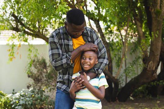 African American father embraces a joyful son in a sunny garden