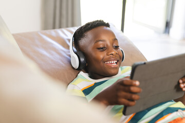 African American boy enjoys a tablet while wearing headphones