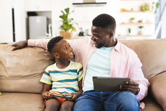 African American father and son share a moment with a tablet on the couch