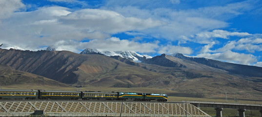 Fototapeta premium The train passes in front of the snow-capped mountains in Tibet