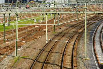 A network of brown rusted railroad tracks and overhead lines at a railroad station