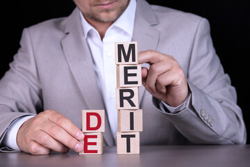 DEMERIT, the word is written on wooden cubes, blocks on the background of a man, a businessman in a...