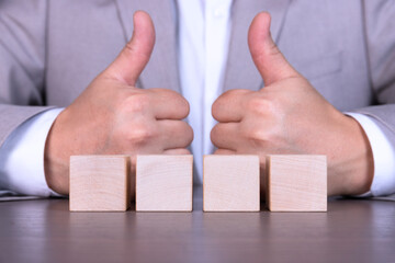 A businessman adds four wooden cubes with empty space for icons, free space for letters, numbers, symbols or labels.