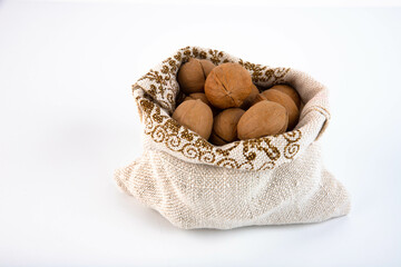Organic fresh harvested walnuts in burlap sack on white background Copy space