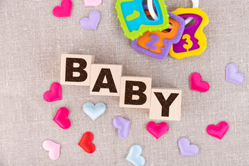 Wooden blocks with the word Baby and small colorful hearts underneath. View from above
