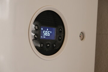 Front panel of gas combi boiler with 58,6 celsius and eco sign on the display. Hot water and heating. Electricity