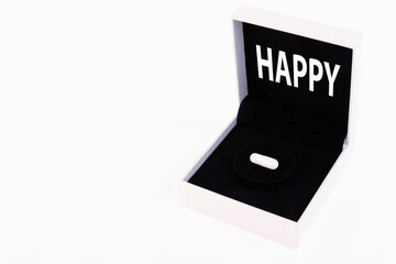 Happy text, White gift box with black velvet and pill, capsule inside, on white background. Copy space.