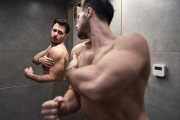 Caucasian man checking muscles in the mirror