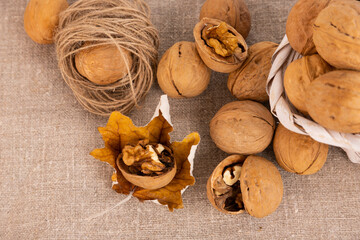 Ripe walnuts in a shell, in a basket and autumn leaves on a linen background. selective focus