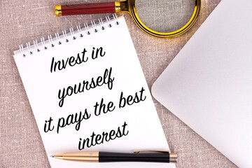 Invest in yourself it pays the best interest, the text is written in a notebook, next to a pen, a...