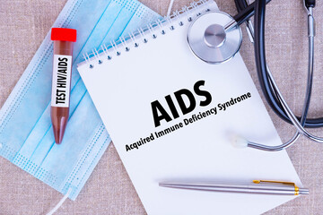 AIDS Acquired Immune Deficiency Syndrome, the text is written in a notebook, next to a pen, a...