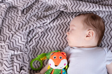 Naklejka premium Adorable child, with a favorite toy, sleeps relaxed and sprawls on the parents' bed