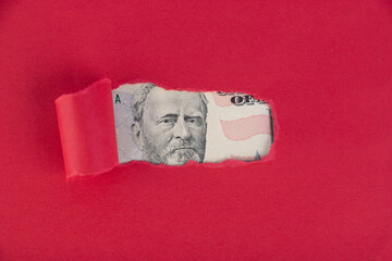 A red background, from under which a portrait of a fifty dollar bill peeps. Borrowed money concept