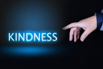 KINDNESS text, word written in neon letters on a black background pointed to by a hand with a...