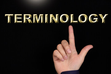 TERMINOLOGY text, a word written on a black background pointed to by a hand with the index finger of a person.