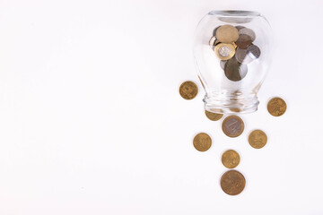 Metal coins pouring out of the can, on a white background. Copy space.