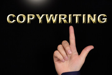 COPYWRITING text, a word written on a black background pointed to by a hand with the index finger of a person.