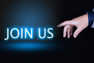 JOIN US text is a word written in neon letters on a black background pointed to by a hand with a person's index finger.