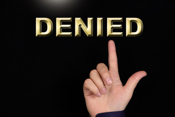DENIED text, a word written on a black background pointed to by a hand with the index finger of a person.