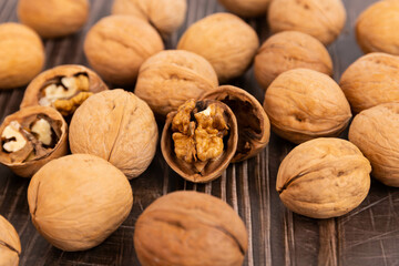 Walnut kernels and whole walnuts on a rustic old wooden table.