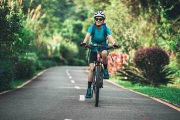 Woman cycling on tropical park trail in summer