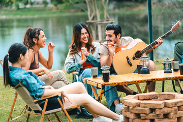 A group of people are sitting around a table with a guitar and a fire pit