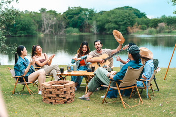 A group of people are sitting around a table with a guitar and a fire pit