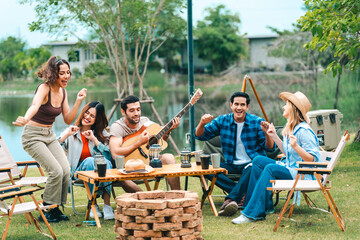 A group of people are sitting around a table with a guitar and a fire pit - 756267174