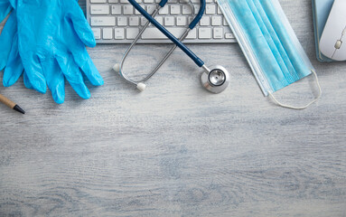 Medical mask, gloves, stethoscope and computer keyboard on the table.