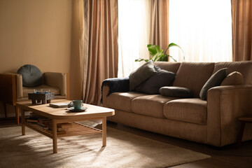 Interior design with beige sofa and wooden coffee table, gray cushions, morning light with sun rays