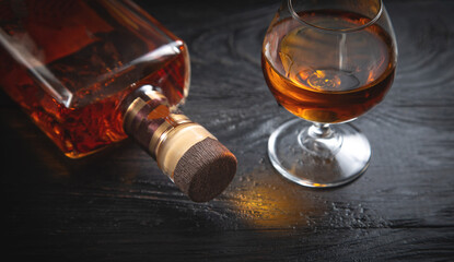 Glass of cognac and bottle on the dark background.