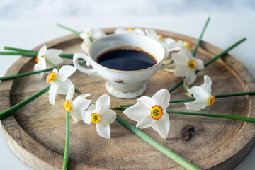 Still life with a delicate decoration of white daffodil flowers around a baroque fine porcelain coffee cup on a wooden tray - 756268705