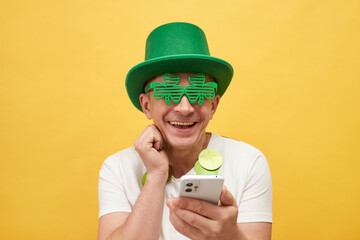 St. Patrick's Day festivities. Joyful man wearing festive green hat and shamrock glasses standing...