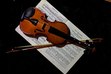A photo of a violin and sheet music against a dark background.