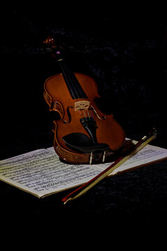 A photo of a violin and sheet music against a dark background.