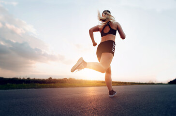 Young Sporty woman running at sunset on the road.Concept of health, slimming and maintaining youth.