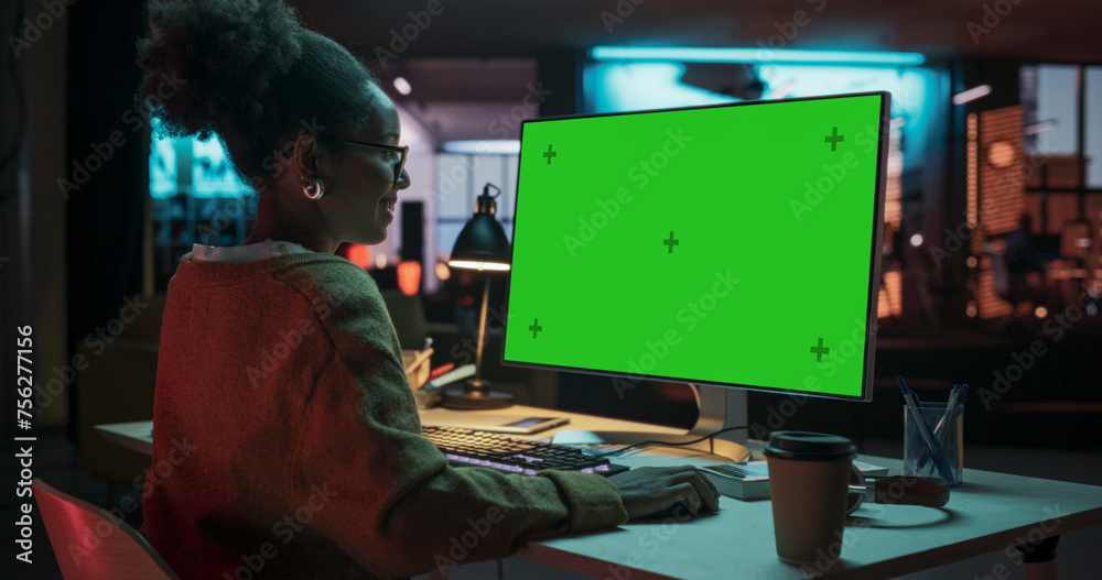 Poster over the shoulder: african female specialist working on computer with chroma key display at creative