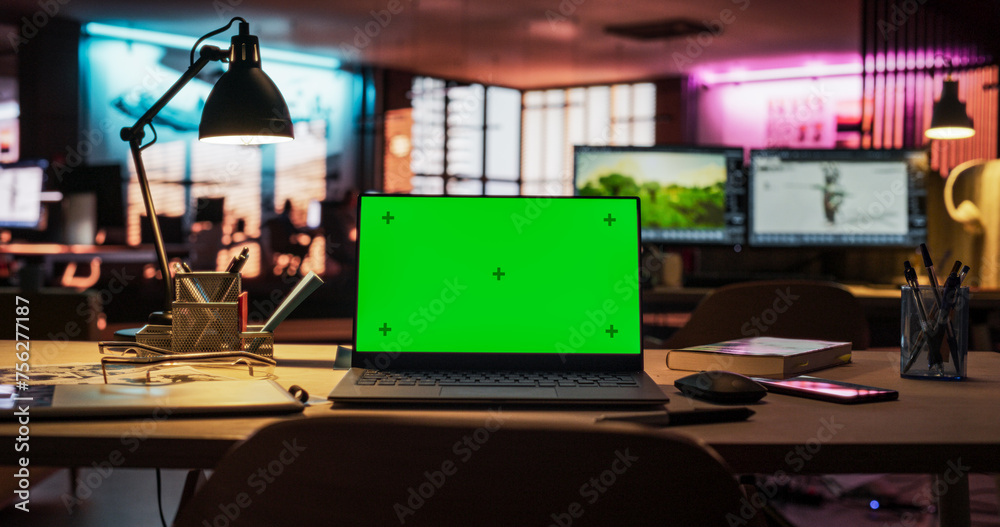 Poster Laptop Computer Standing on a Wooden Desk with a Green Screen Chromakey Mock Up Display. Creative Office Working Station for Game Developer and Graphic Designer in Creative Agency