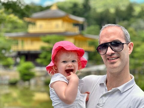 Enfant fille de 1 an et demi dans les bras de son papa devant une pagode au Japon