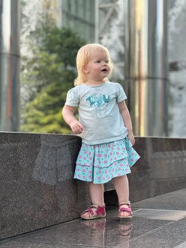 Enfant fille de 1 an et demi accoudée à un monument public moderne